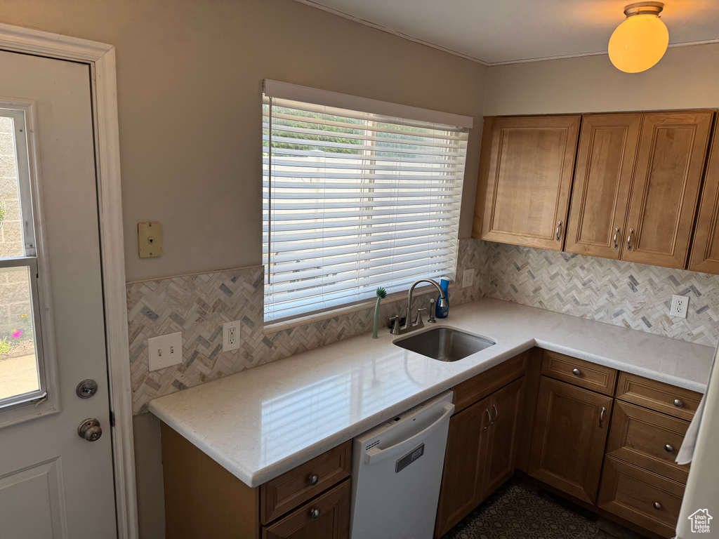 Kitchen featuring dishwasher, light countertops, brown cabinets, and decorative backsplash