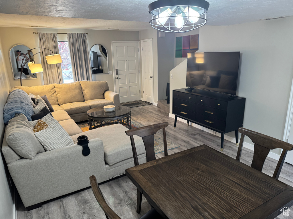 Living area with wood finished floors, a chandelier, and a textured ceiling