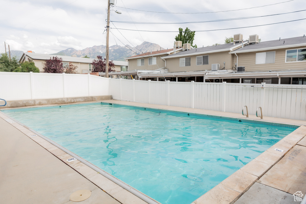 Community pool with a mountain view and a fenced backyard