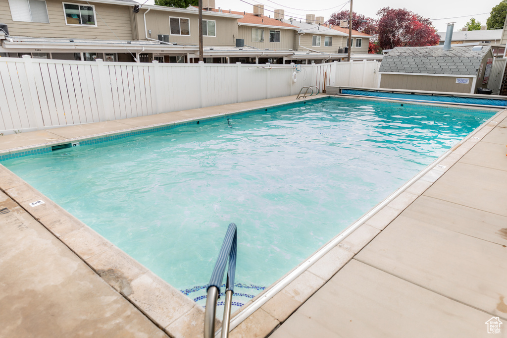 Community pool featuring a fenced backyard and a shed