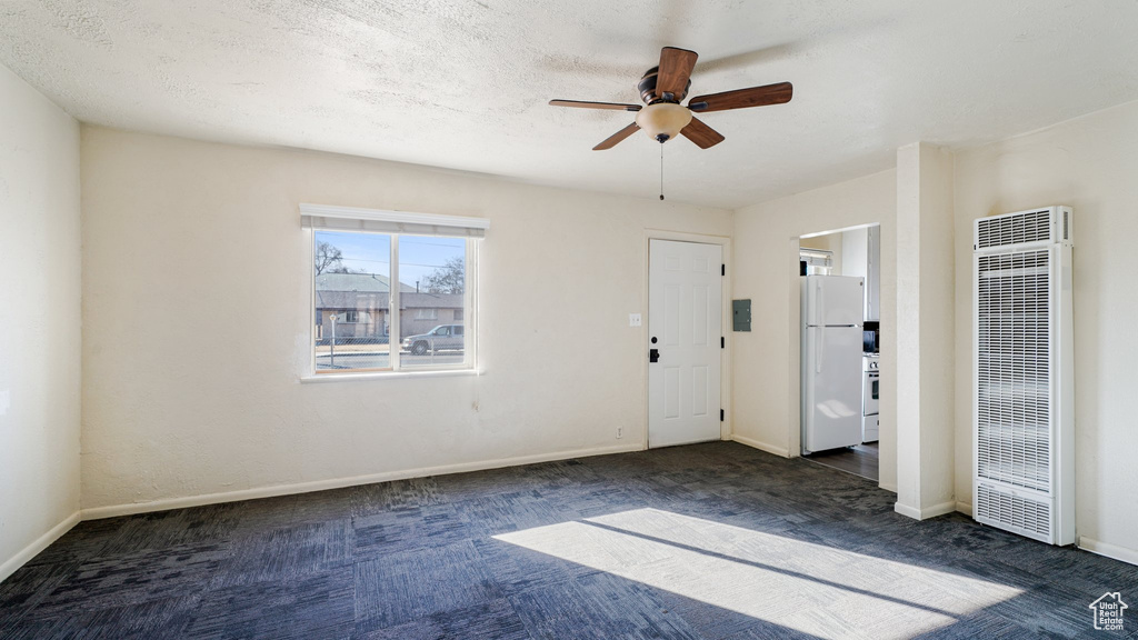Spare room with a heating unit, a ceiling fan, and carpet floors