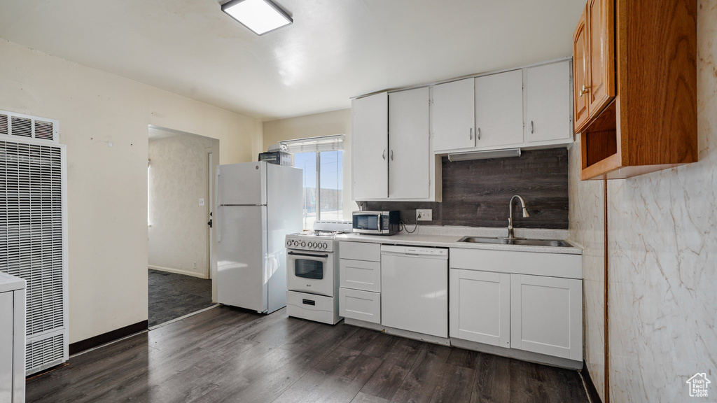 Kitchen featuring white appliances, dark wood finished floors, a heating unit, light countertops, and white cabinetry