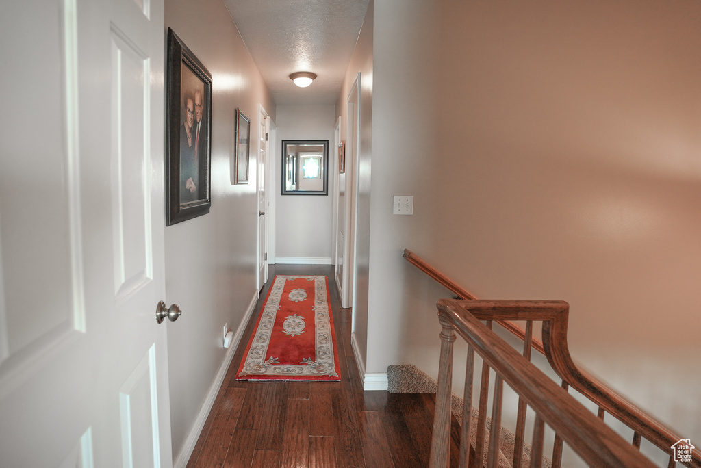 Hallway featuring an upstairs landing, wood finished floors, and a textured ceiling