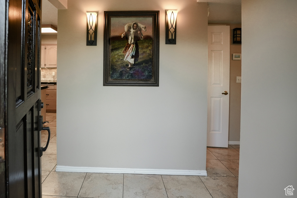 Corridor featuring baseboards and light tile patterned flooring