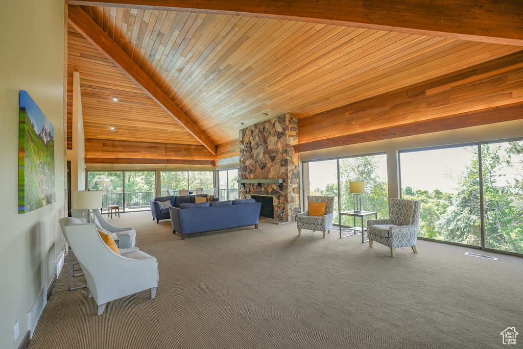 Carpeted living area with wooden ceiling, a fireplace, and high vaulted ceiling
