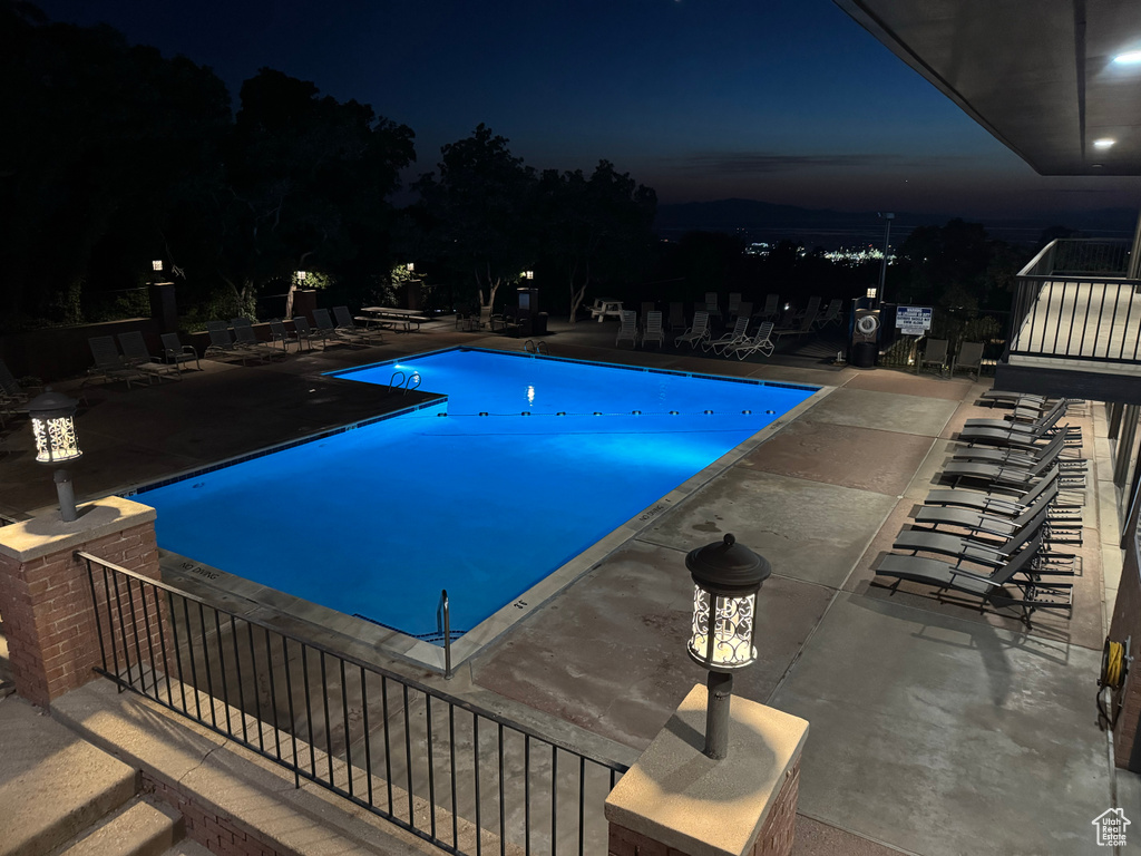 Pool at night with a patio area and a community pool