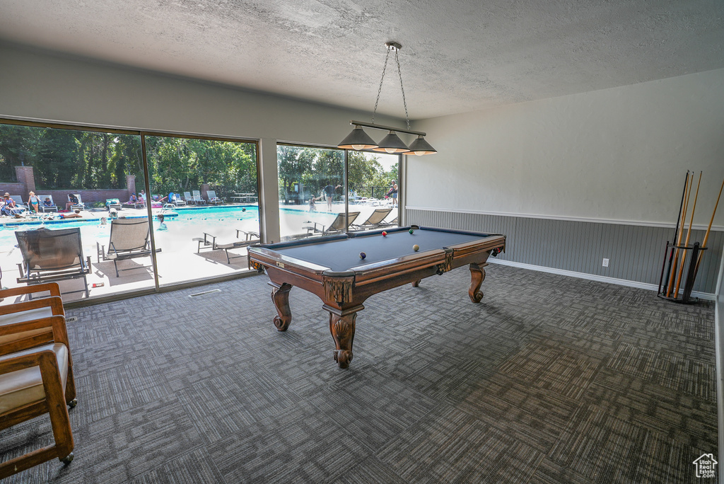 Recreation room featuring a textured ceiling, carpet, billiards, and a wainscoted wall