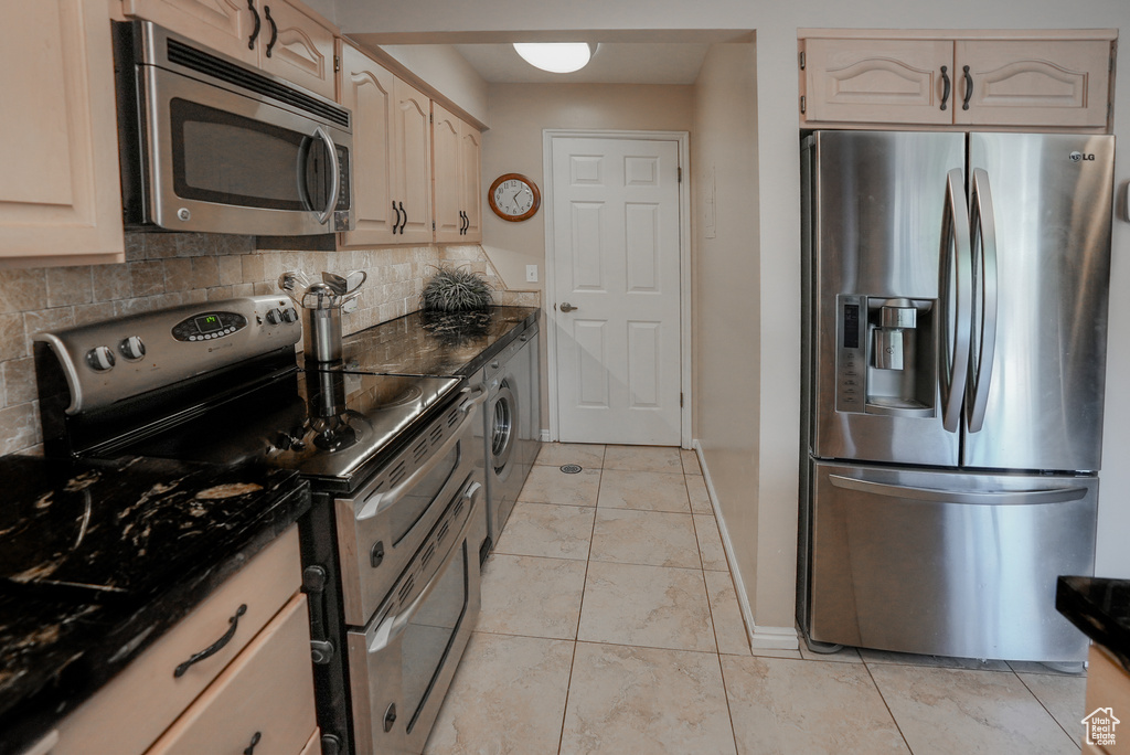 Kitchen with appliances with stainless steel finishes, decorative backsplash, and washer / clothes dryer