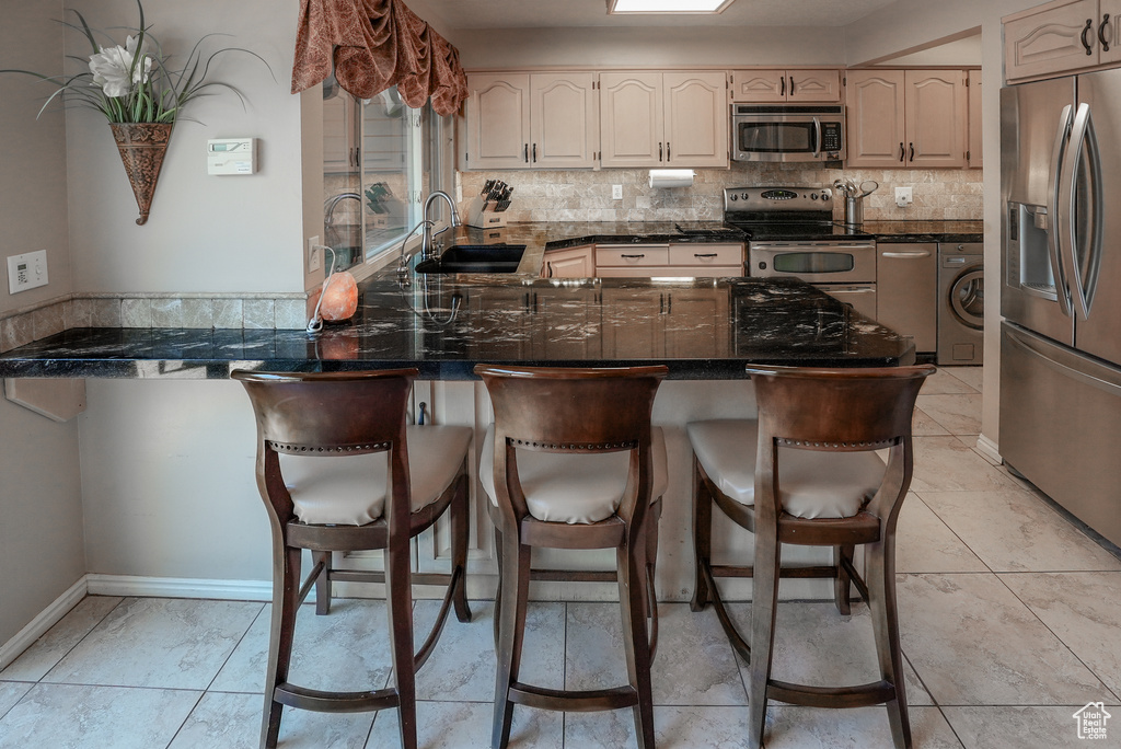 Kitchen with stainless steel appliances, washer / dryer, a peninsula, and backsplash