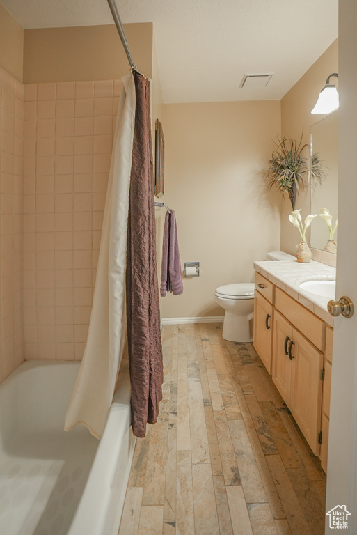 Full bathroom with vanity, shower / bath combination with curtain, and wood-type flooring