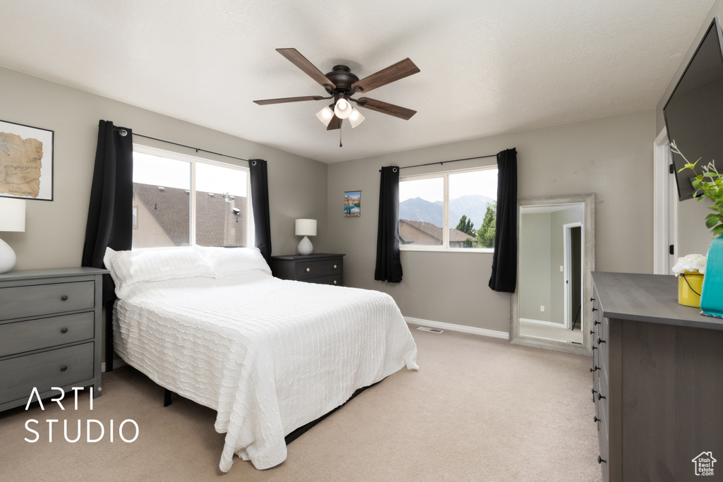 Bedroom with multiple windows, light carpet, and ceiling fan