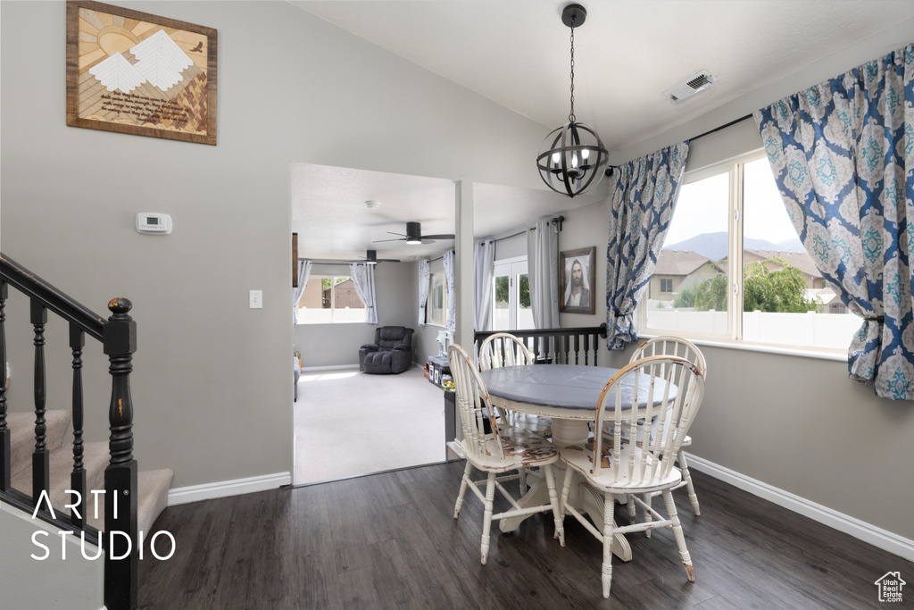 Dining space featuring wood finished floors, a chandelier, lofted ceiling, plenty of natural light, and a ceiling fan
