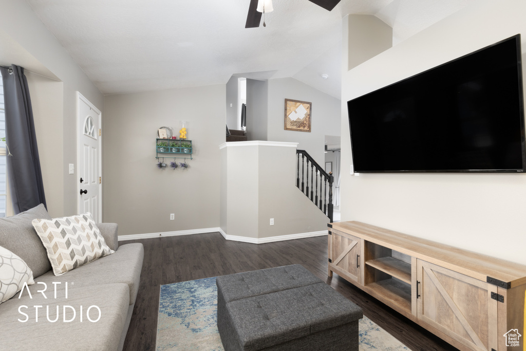 Living room featuring dark wood-type flooring, a ceiling fan, and vaulted ceiling