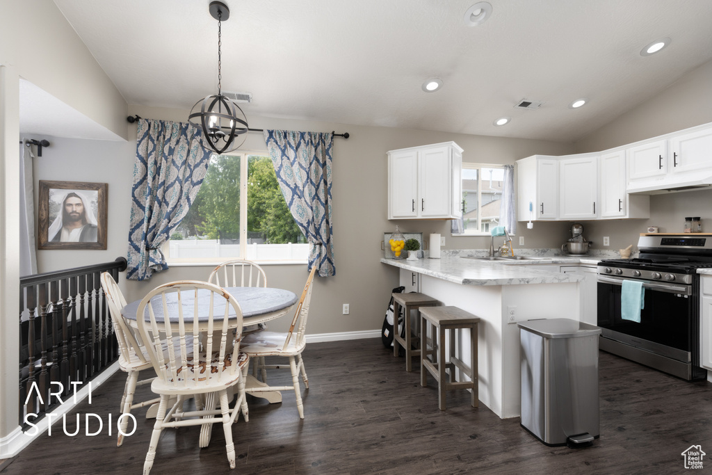 Kitchen featuring stainless steel range with gas cooktop, under cabinet range hood, dark wood-style floors, white cabinets, and recessed lighting