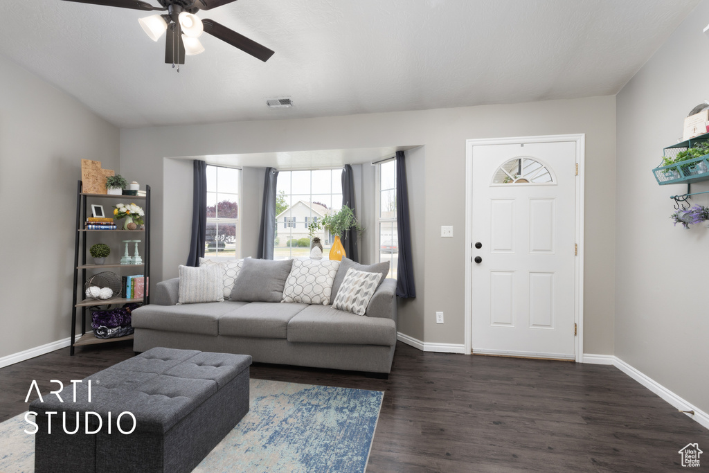 Living room with a ceiling fan and dark wood-type flooring