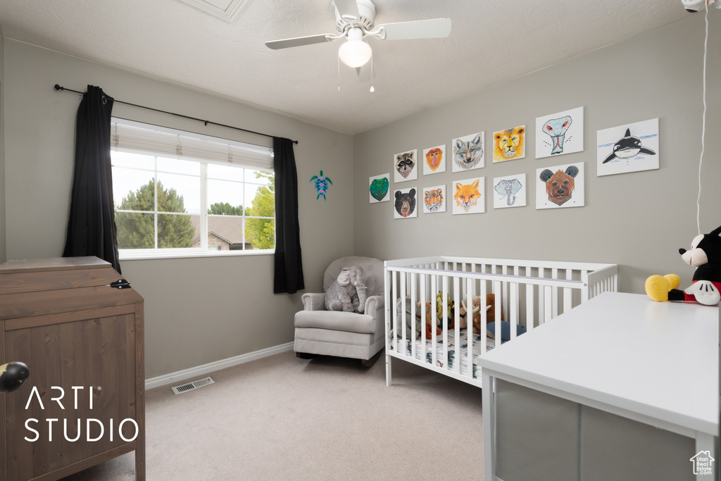 Bedroom with a crib, carpet flooring, and ceiling fan