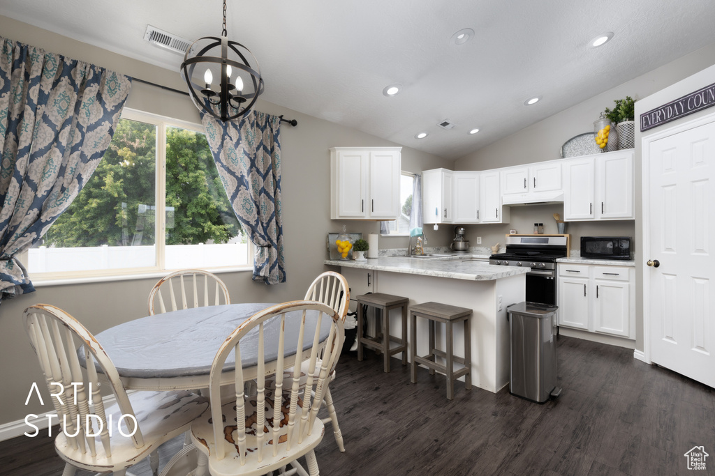 Kitchen with stainless steel range, black microwave, a chandelier, white cabinetry, and lofted ceiling