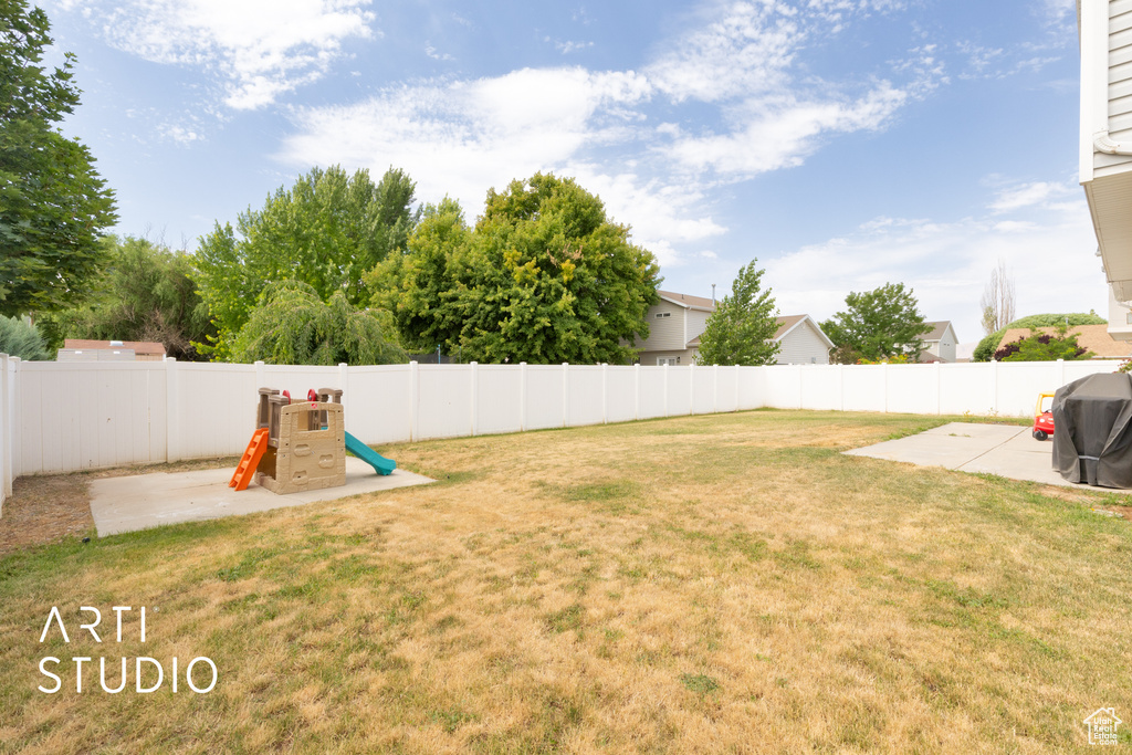Fenced backyard featuring a patio area and a playground