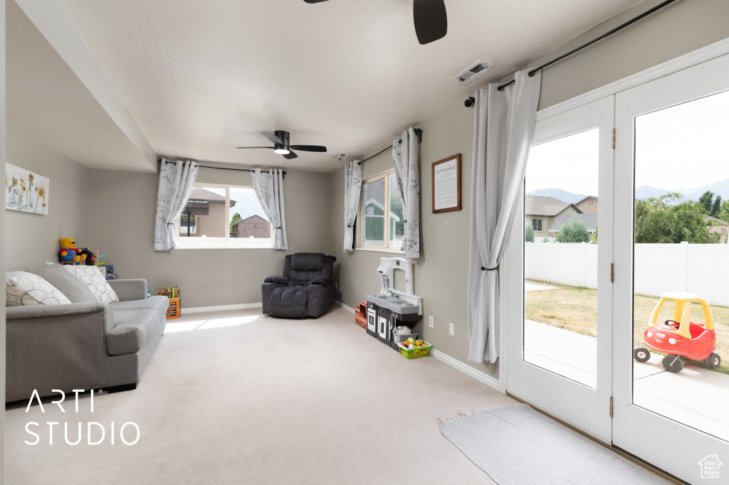 Carpeted living room with ceiling fan and baseboards