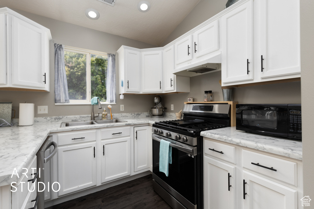 Kitchen featuring stainless steel appliances, vaulted ceiling, white cabinets, under cabinet range hood, and dark wood-type flooring