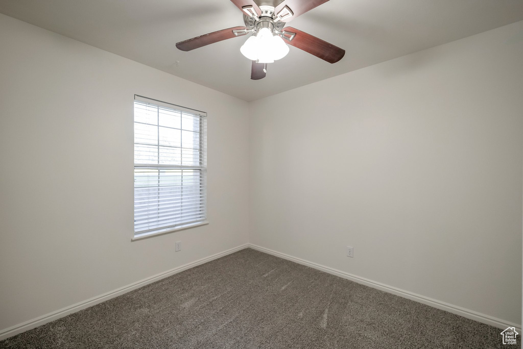 Spare room featuring dark carpet and a ceiling fan