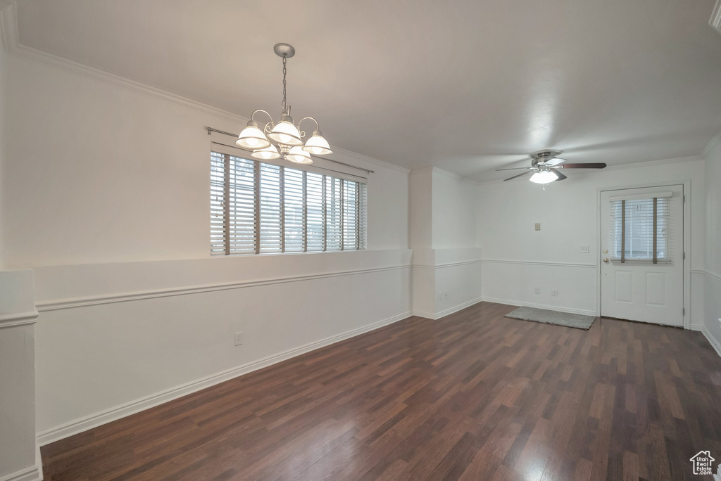 Unfurnished room with dark wood finished floors, plenty of natural light, crown molding, a chandelier, and ceiling fan