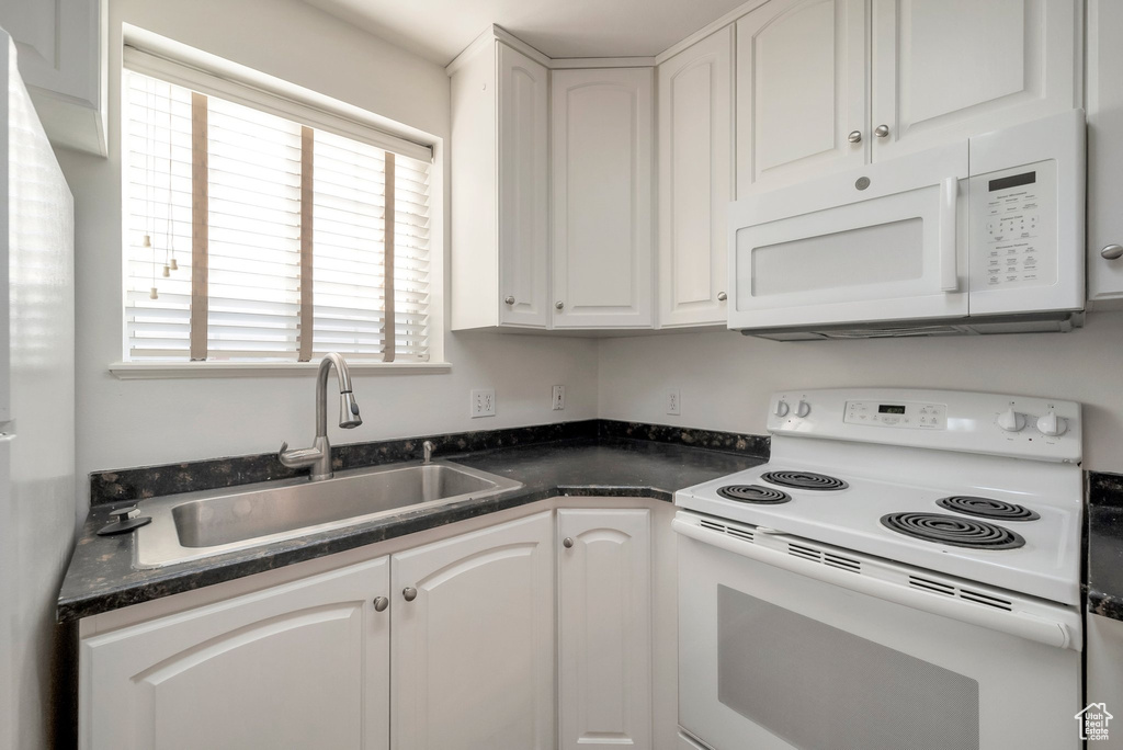 Kitchen with white appliances, dark countertops, and white cabinets
