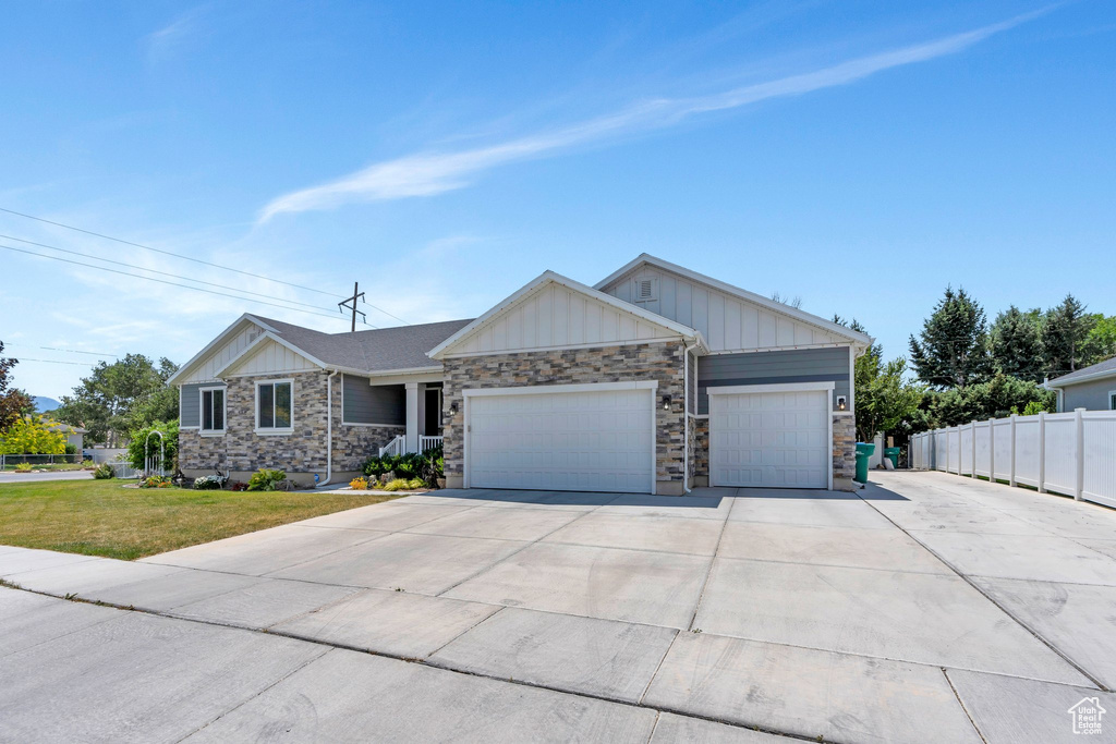 Ranch-style home with board and batten siding, a garage, stone siding, and driveway