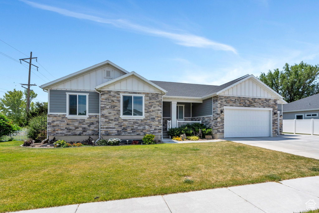 Craftsman-style house featuring board and batten siding, a porch, a garage, concrete driveway, and stone siding