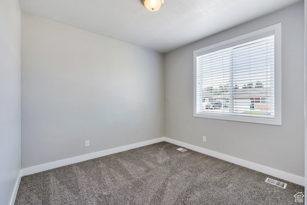 Empty room featuring dark carpet and baseboards
