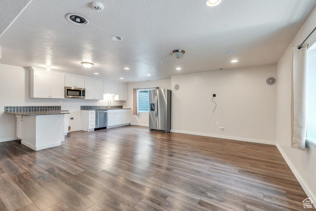 Unfurnished living room featuring dark wood finished floors, recessed lighting, and a textured ceiling