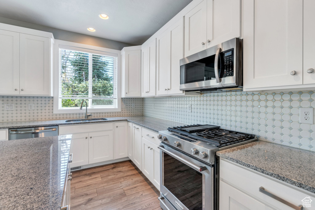 Kitchen featuring appliances with stainless steel finishes, light wood-style floors, white cabinets, and recessed lighting