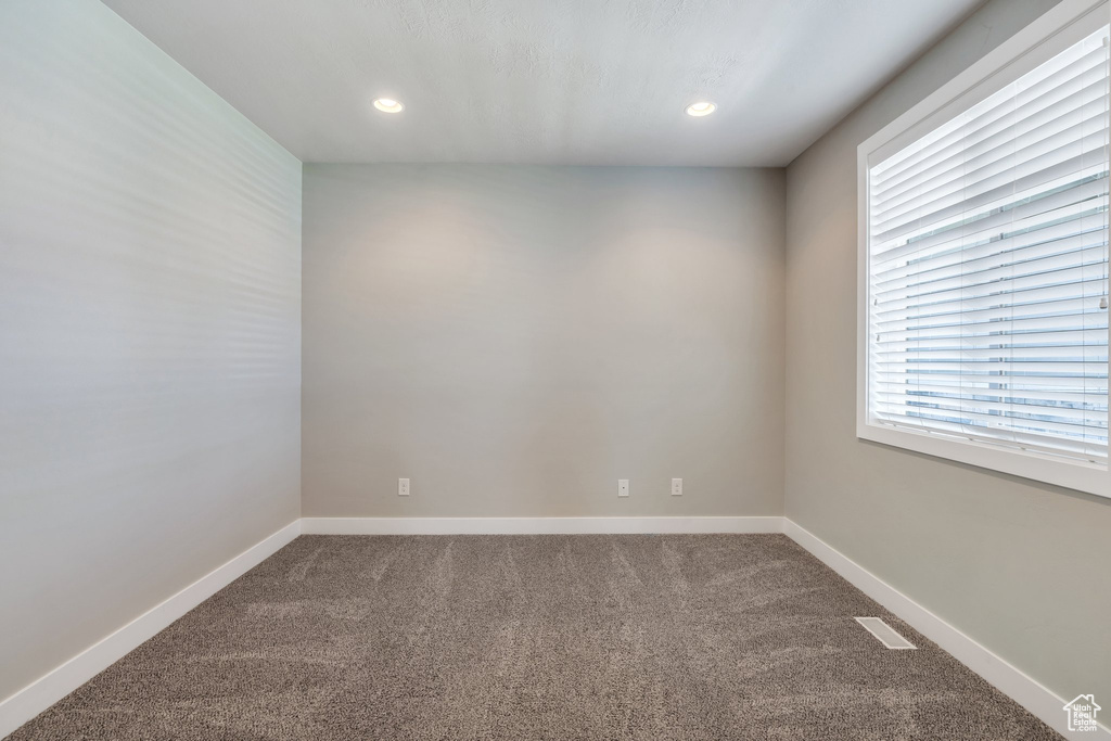 Empty room with dark carpet and recessed lighting