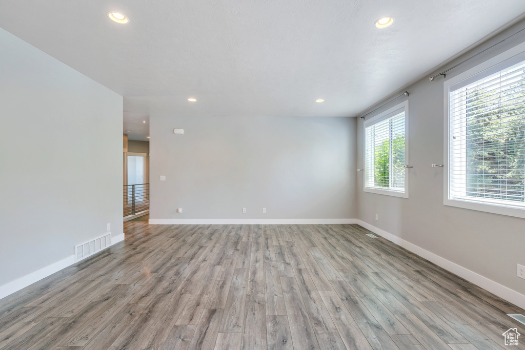 Empty room with light wood-style floors and recessed lighting