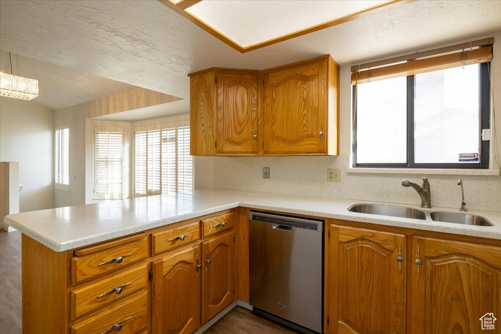 Kitchen featuring dishwasher, a peninsula, brown cabinets, and light countertops