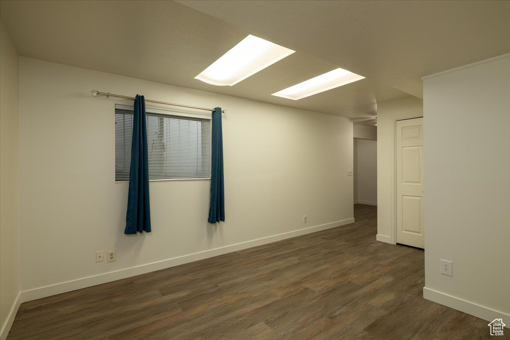 Spare room with dark wood-style floors and baseboards