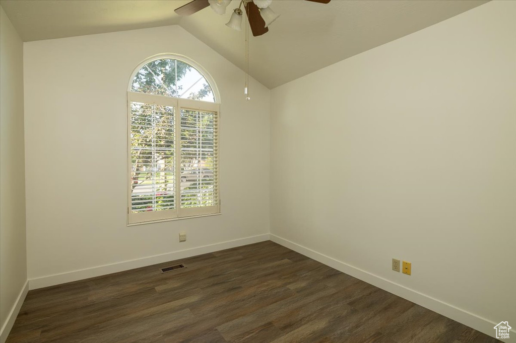 Spare room featuring a ceiling fan, vaulted ceiling, and dark wood finished floors