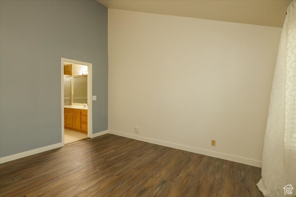 Empty room featuring dark wood finished floors and high vaulted ceiling
