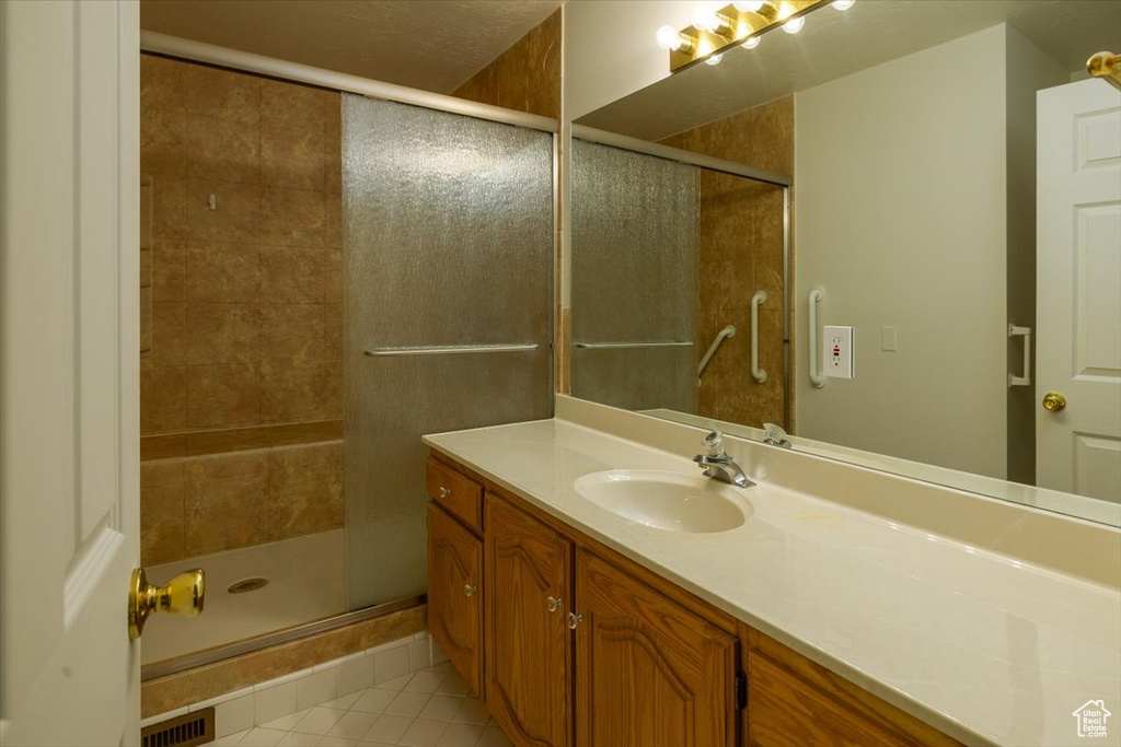 Bathroom with tile patterned floors, vanity, and a stall shower