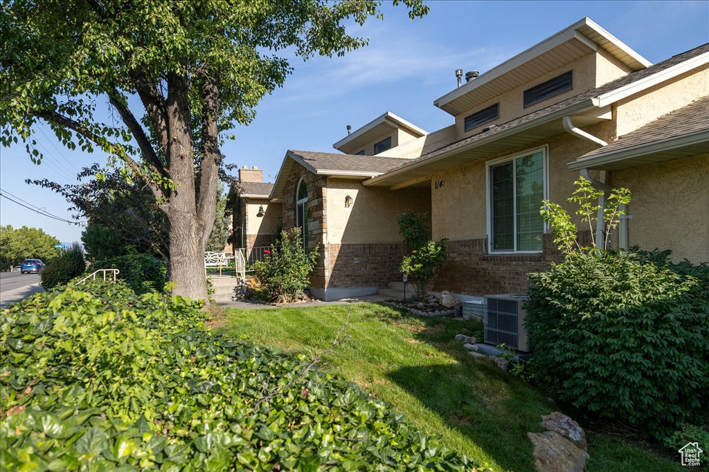 View of home's exterior with stucco siding, a yard, and stone siding