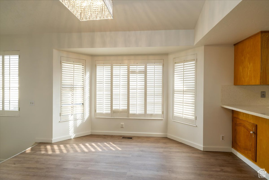 Unfurnished dining area featuring wood finished floors, plenty of natural light, and a chandelier