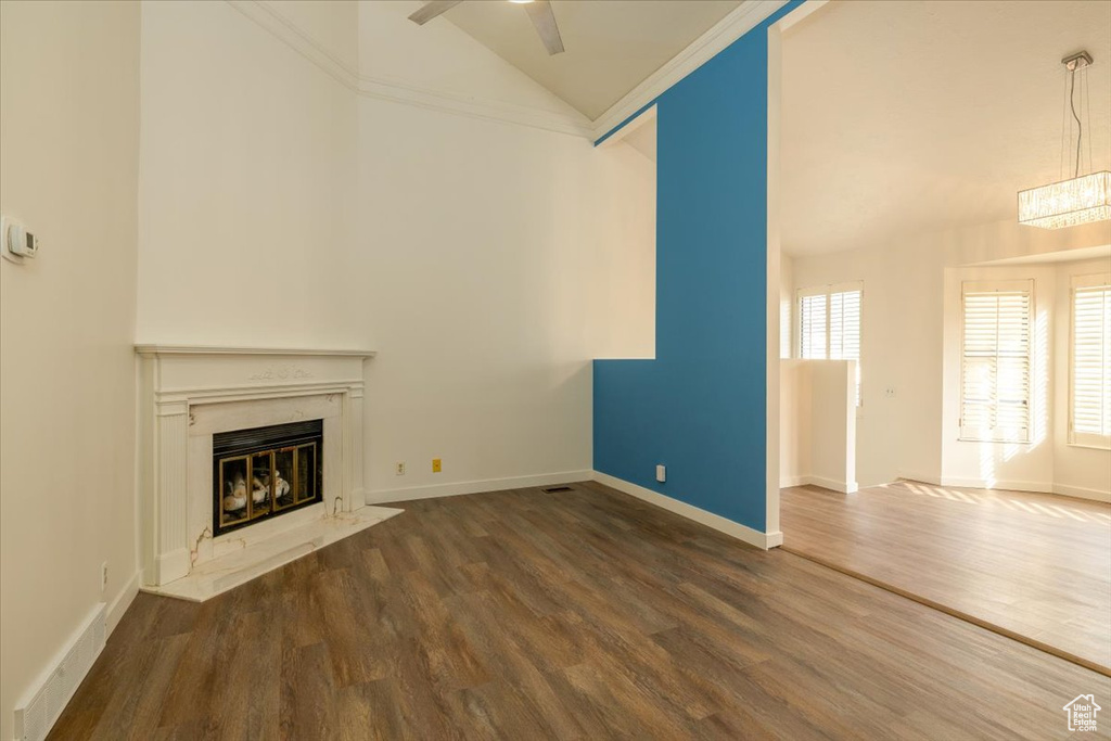 Unfurnished living room with a high end fireplace, wood finished floors, high vaulted ceiling, and ceiling fan