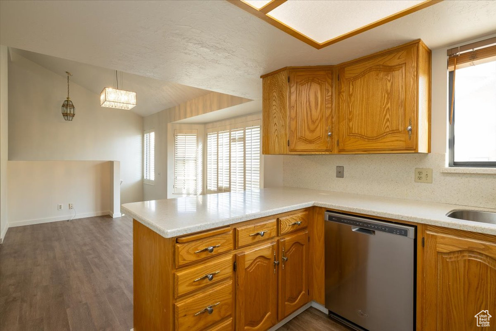 Kitchen featuring stainless steel dishwasher, a peninsula, brown cabinetry, and light countertops