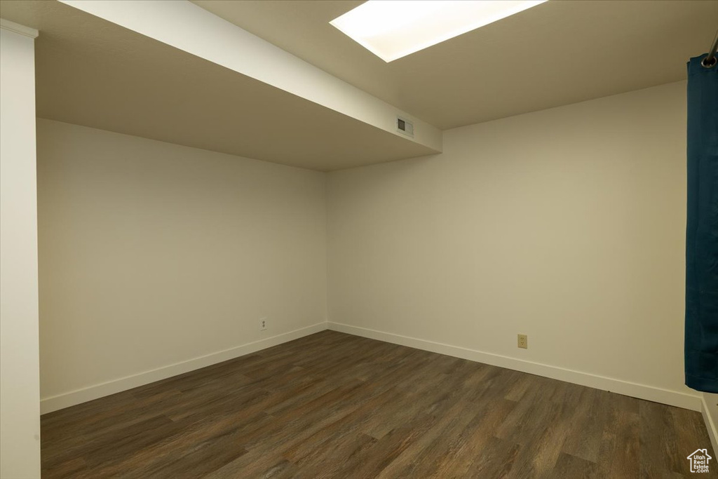 Empty room featuring dark wood-style floors and baseboards