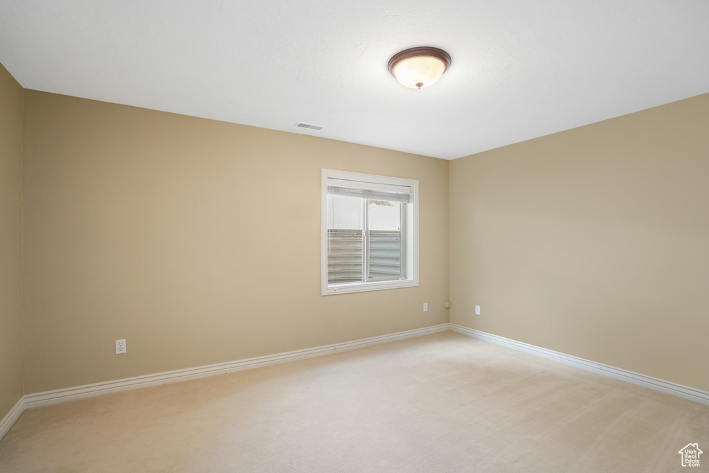 Spare room featuring baseboards and light carpet