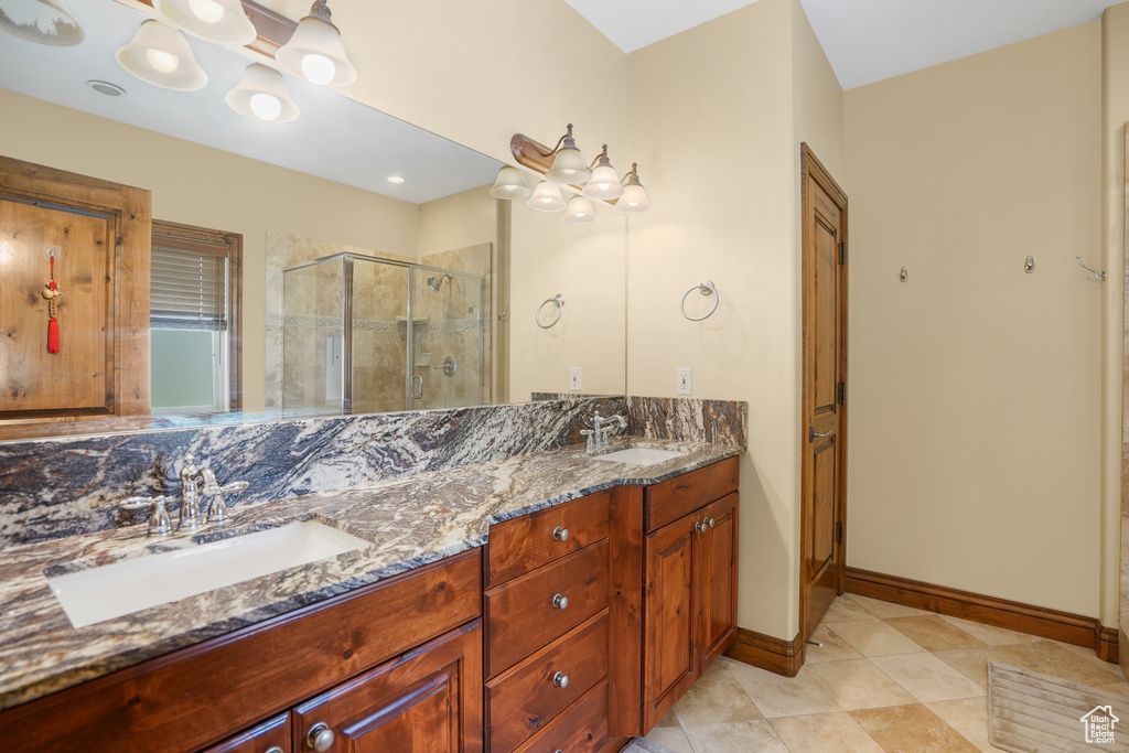 Full bath with a shower stall, double vanity, and tile patterned floors