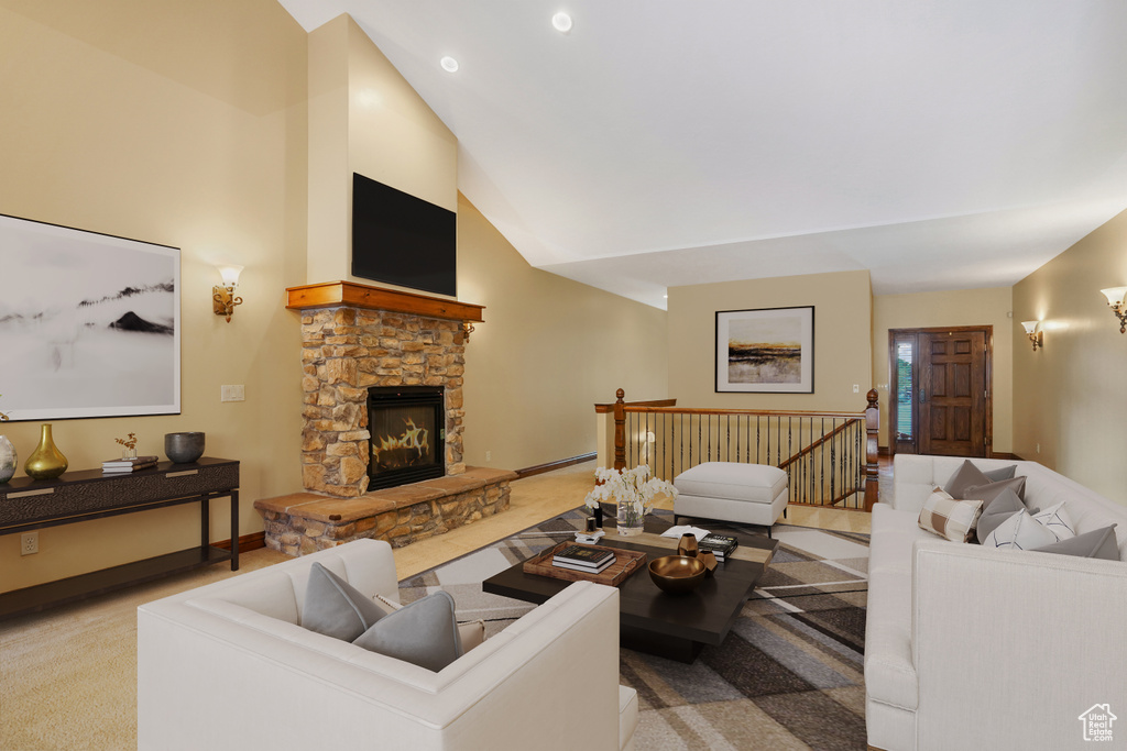 Carpeted living area with high vaulted ceiling, a stone fireplace, and baseboard heating