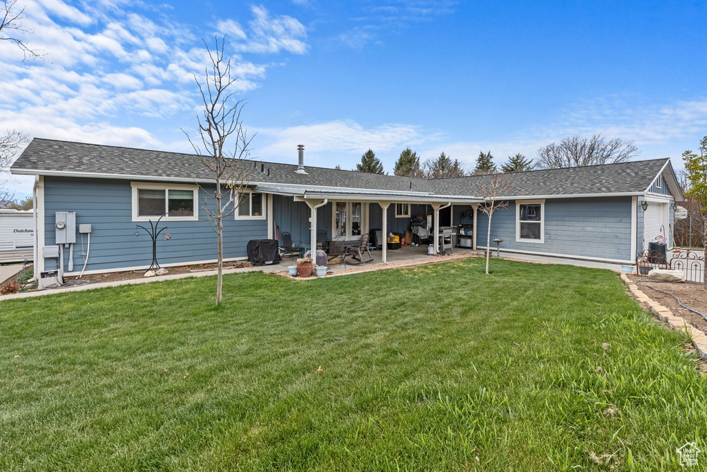 Rear view of house featuring a lawn and a patio