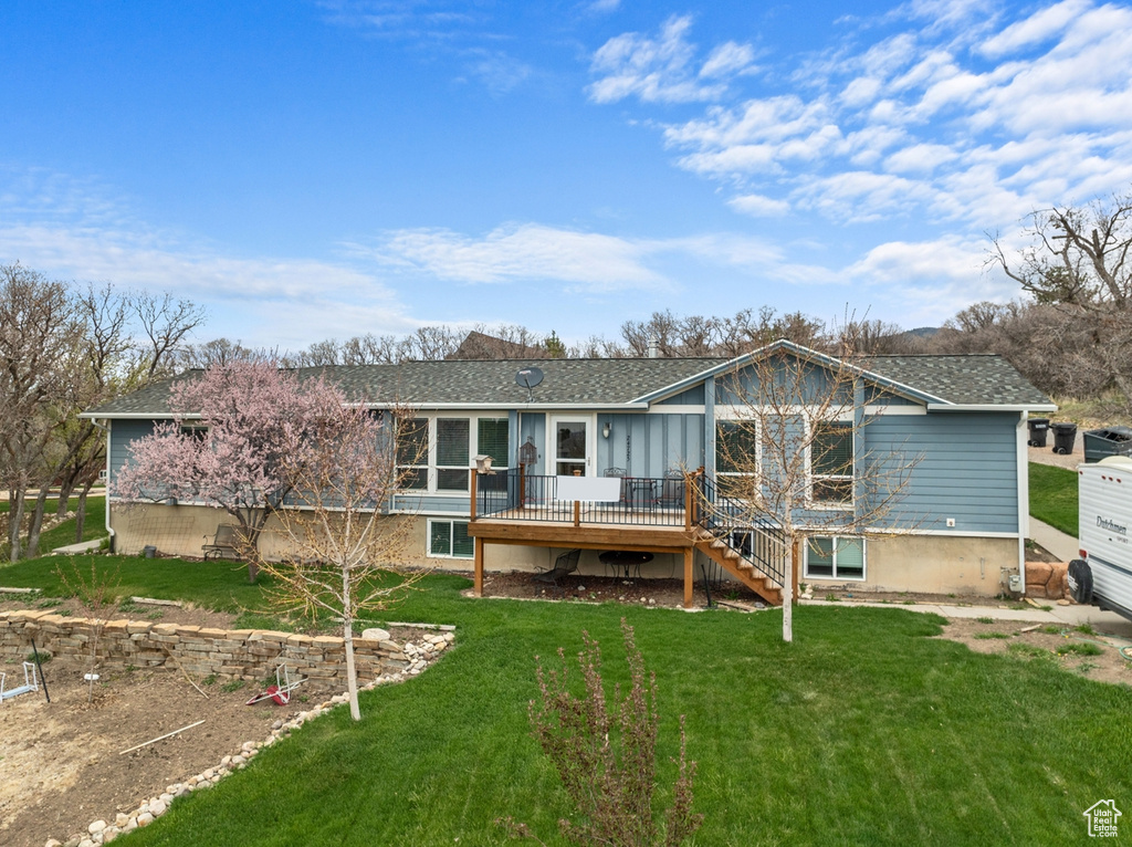 Back of house featuring a wooden deck, stairway, a yard, and a shingled roof