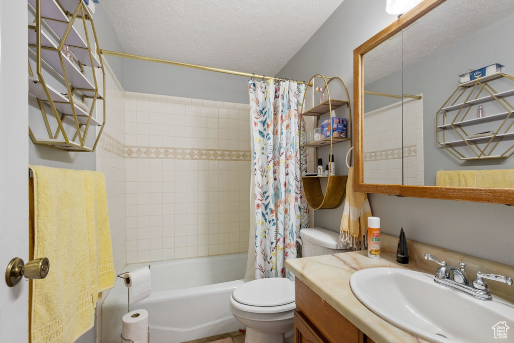 Bathroom featuring vanity, shower / bath combo with shower curtain, and a textured ceiling